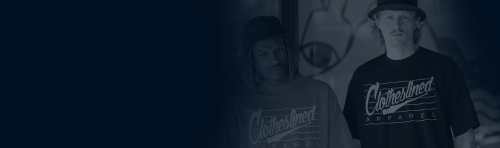 Two people wearing 'Clotheslined' t-shirts standing in front of a mural.